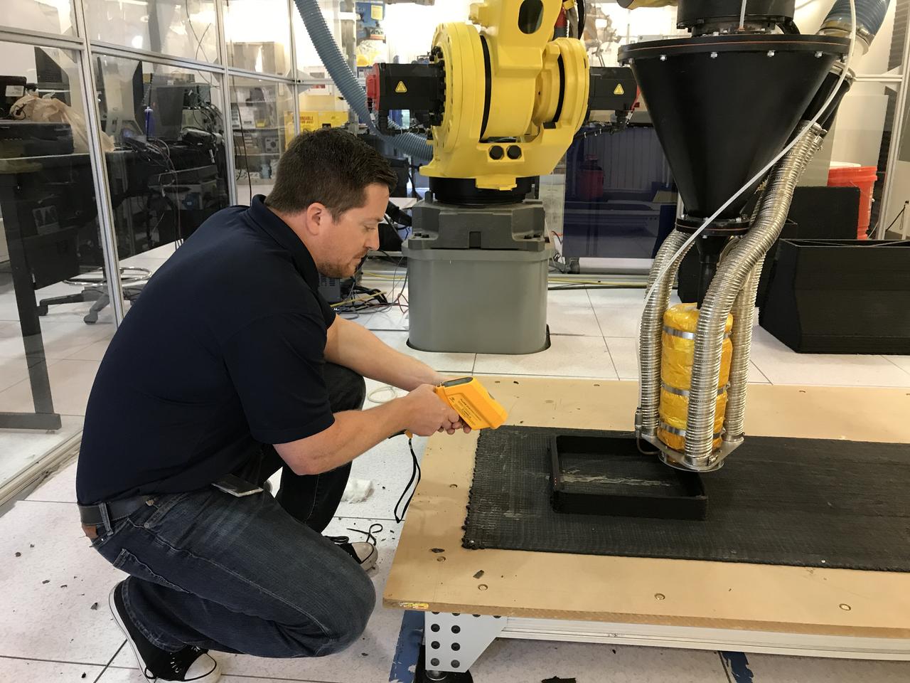 Packing light is the idea behind the Zero Launch Mass 3-D Printer. Instead of loading up on heavy building supplies, a large scale 3-D printer capable of using recycled plastic waste and dirt at the destination as construction material would save mass and money when launching robotic precursor missions to build infrastructure on the Moon or Mars in preparation for human habitation. To make this a reality, Nathan Gelino, a researcher engineer with NASA’s Swamp Works at Kennedy Space Center, measured the temperature of a test specimen from the 3-D printer Tuesday as an early step in characterizing printed material strength properties. Material temperature plays a large role in the strength of bonds between layers.